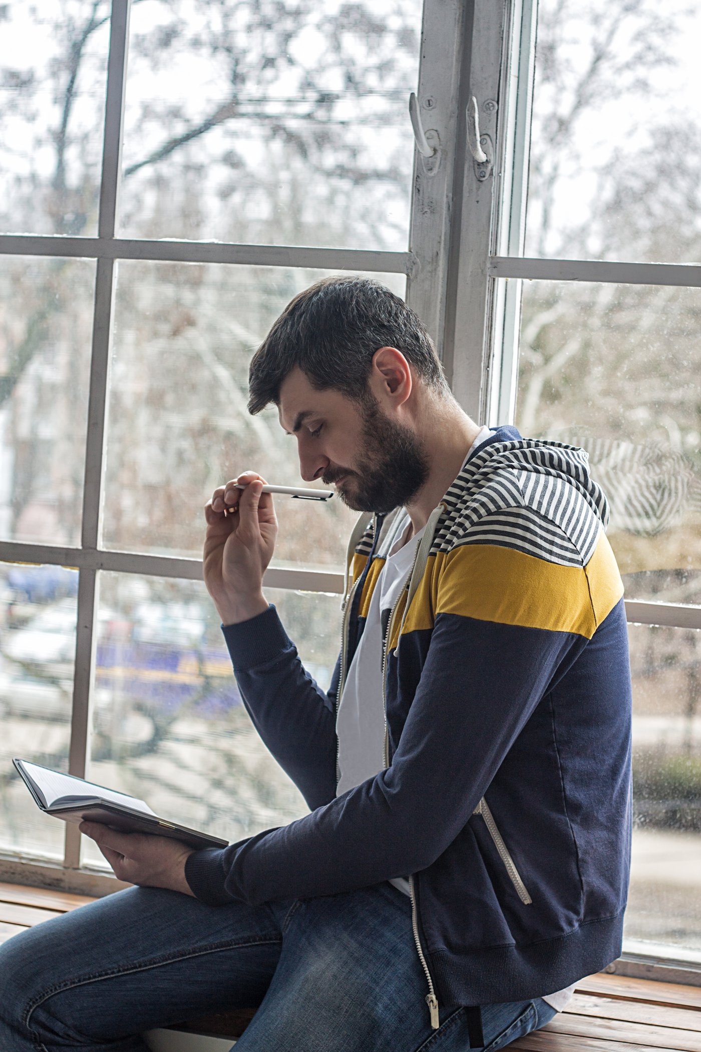 A young professional stopping to think before acting - pen in hand, notebook open.